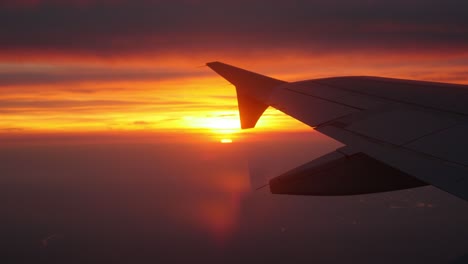 Window-point-of-view-of-the-sunrise-in-a-plane,-seeing-wing-aircraft.-Paris